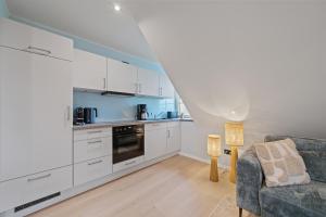 a kitchen with white cabinets and a couch at Nordseebude Deichtraum in Sankt Peter-Ording +21 photos