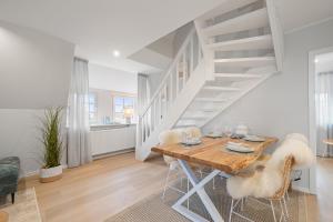 a dining room with a wooden table and stairs at Nordseebude Deichtraum in Sankt Peter-Ording