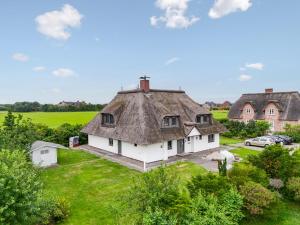 an old house with a thatched roof in a field at Nordseebude Deichtraum in Sankt Peter-Ording