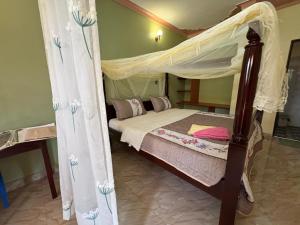 a bedroom with a canopy bed with white curtains at Palm Garden Guest House in Gulu