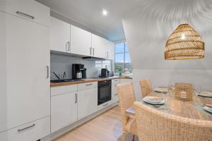 a kitchen with white cabinets and a table with chairs at Nordseebude Küstenglück in Sankt Peter-Ording