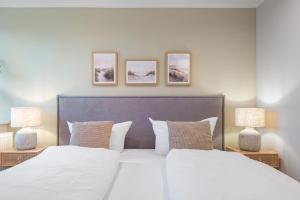 a bedroom with a large white bed with two lamps at Nordseebude Küstenglück in Sankt Peter-Ording