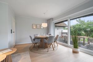 a dining room with a table and chairs and a large window at Nordseebude Strandnest in Sankt Peter-Ording