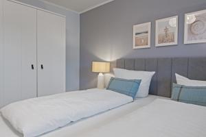a white bedroom with two beds and a lamp at Nordseebude Strandnest in Sankt Peter-Ording