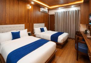 two beds in a hotel room with a desk and a bed at Hotel happy stay inn in Pashupatināth +9 photos
