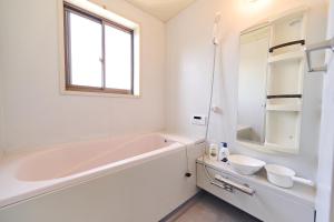 a white bathroom with a tub and a sink at Kokonimo Yotsukaido in Yotsukaidō