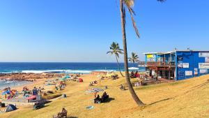 people on a beach with palm trees and the ocean at Oceans Whisper 704 beach apartment gated & Lift access in Scottburgh