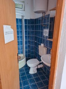a blue tiled bathroom with a toilet and a sink at Camping 999 Jablaničko jezero in Železnička Stanica Ostrožac