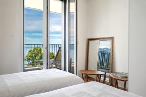 a bedroom with two beds and a balcony at Terrasses de Lavaux-3 Luxe & Détente Terrasse Piscine Vue Montagnes et lac in Puidoux