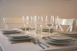 a table with wine glasses and plates and silverware at Plage & Montagne - Appartement familial à proximité de la plage de Préverenges in Preverenges