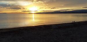 a sunset over the water with people walking on the beach at Plage & Montagne - Appartement familial à proximité de la plage de Préverenges in Preverenges +22 photos