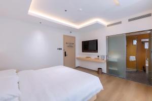 a white bedroom with a large bed and a tv at Hera Hotel in Hanoi