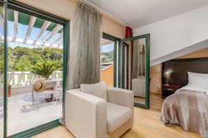 a bedroom with a bed and a chair and a balcony at Apartments Grifone Lux in Herceg-Novi +161 photos