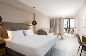 a bedroom with a large white bed and a living room at Portes Lithos Luxury Resort in Nea Potidaea +62 photos