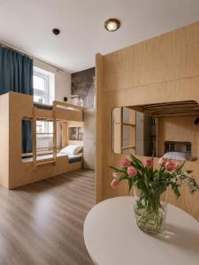 a vase of flowers on a table in a room with bunk beds at Dzien Dobry Hostel in Gdańsk