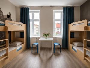 two beds in a room with a table and two stools at Dzien Dobry Hostel in Gdańsk