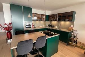 a kitchen with green cabinets and a table and chairs at Les Terrasses de Lavaux-2 Appartement de Luxe avec Vue Panoramique et Piscine" in Chexbres