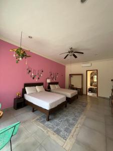 a bedroom with two beds and a pink wall at Casa Sayab Hotel Boutique in Maní