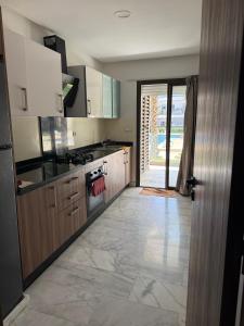 a kitchen with wooden cabinets and a door to a patio at Blue water house in Dar Bouazza
