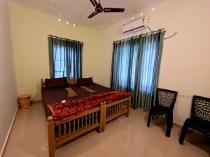 a bedroom with a bed and two chairs in it at Beach Way Villa in Varkala