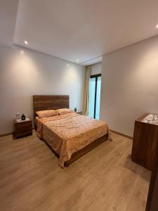 a bedroom with a large bed and a large window at Blue water house in Dar Bouazza