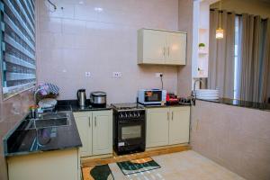 a kitchen with white cabinets and a stove top oven at ExtraMile Apartments - 2BR in Dodoma