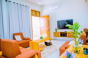 a living room with orange chairs and a tv at ExtraMile Apartments - 2BR in Dodoma