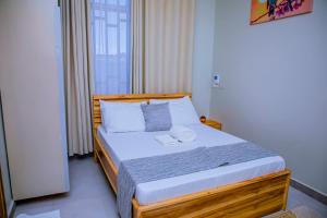 a bedroom with a wooden bed with white pillows at ExtraMile Apartments - 2BR in Dodoma