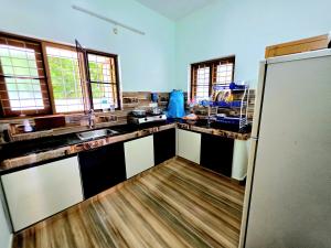 a kitchen with black and white counters and a refrigerator at Beach Way Villa in Varkala