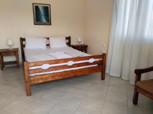 a bedroom with a bed with white sheets and two tables at Christos House in Zárakes +11 photos