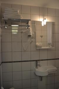 La salle de bains est pourvue de carrelage blanc, d'un lavabo et d'un miroir. dans l'établissement La Casa Mia, à Sainte-Maxime