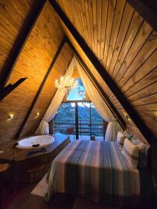 a bedroom with a bed and a tub in a attic at Chalé Cristal Capivari in Campos do Jordão