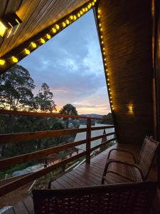 a porch with two chairs and a view of the sunset at Chalé Cristal Capivari in Campos do Jordão
