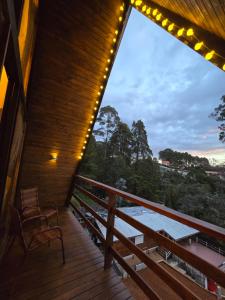 a balcony with a table and chairs and lights at Chalé Cristal Capivari in Campos do Jordão
