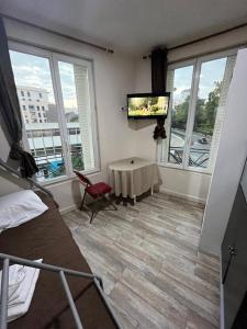 a bedroom with a tv and a table and windows at myappart - colombes in Colombes
