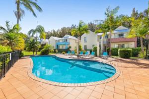 a pool in front of a house with palm trees at Bec's Beach House Getaway in Batemans Bay