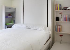 a bedroom with a bed with white sheets and books at Funway Academic Resort in Madrid