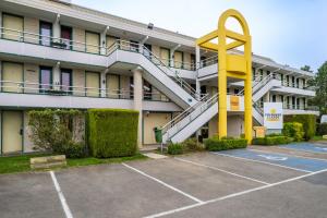 a large building with a yellow spiral staircase in a parking lot at Premiere Classe Liege / Luik in Liège