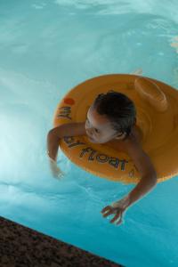 a young man in a pool with a raft in the water at Runo Apartamenty & SPA - Basen Sauna - Odkryj-Białkę in Białka Tatrzańska