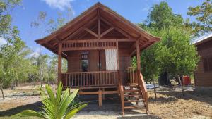 a small wooden cabin with a porch in a yard at FURUSATO BUNGALOW Gili Gede in Gili Gede