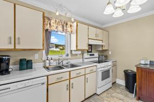 a kitchen with white cabinets and a sink and a window at Westward Oceanfront Sunsets over Trinity Bay in Hearts Delight