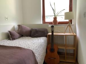 a bedroom with a guitar next to a bed with a window at Elly Apartment - 20 min to Ljubljana in Kresnice
