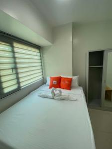 a white bed with orange pillows and towels on it at MyHappyPlace Elements in Manila