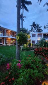 a building with a palm tree and some flowers at Hillview Beach Resort in Varkala