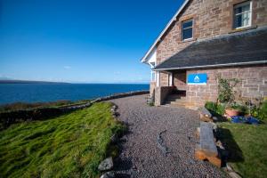 a brick building with a sign on it next to the water at Gairloch Sands Youth Hostel in Gairloch
