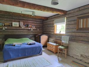 a bedroom with wooden walls and a bed and a chair at Kooti Ait in Korjuse