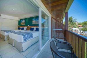 a bedroom with a balcony with a bed and chairs at Salinas Maceio All Inclusive Resort in Maceió