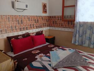 a bedroom with a large bed with red pillows at Hotel restaurant ait saderat in Boumalne Dades
