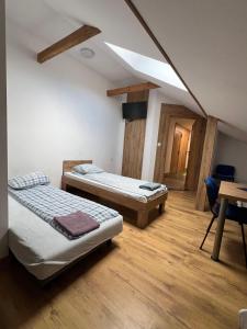 a room with two beds and a table with a desk at Rezydencja pod Gwiazdami in Legarda