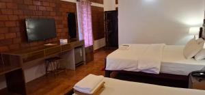 a hotel room with two beds and a television at Hillview Beach Resort in Varkala